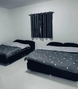 2 Betten in einem Zimmer mit schwarzen Vorhängen in der Unterkunft Pool Villa Sattahip White House in Sattahip