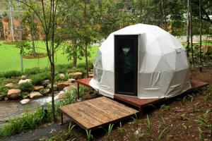 a tent in a garden with a wooden bench at LTC Dalat Villa & Resort in Ðưc Trọng