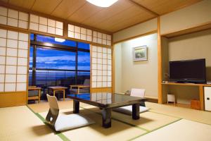 a living room with a table and a large window at Motoyu Kosenkaku in Kobe