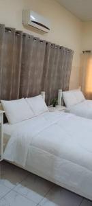 a bedroom with two white beds and a curtain at Marrets International Villa in Accra