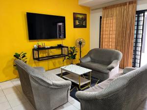 a living room with chairs and a tv on a yellow wall at Big Dreams Double Story House in Tanah Rata
