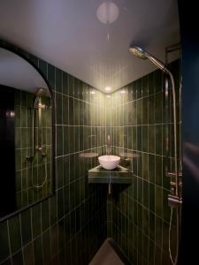 baño de azulejos verdes con lavabo y ducha en The Box Car with Outdoor Private Bath, en Closeburn