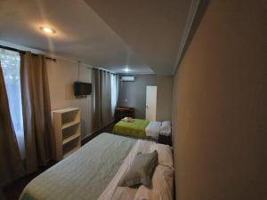 Habitación pequeña con 2 camas y TV. en Hotel Villarrica Centro en Villarrica