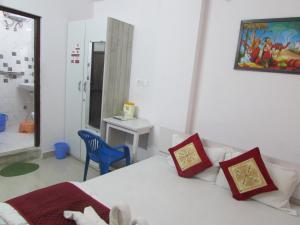 a bedroom with a white bed and a blue chair at Ashish Guest House, Udaipole in Udaipur