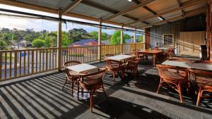 a screened in porch with tables and chairs at Union Hotel Tumbarumba in Tumbarumba