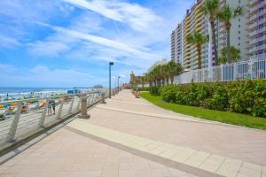 a sidewalk next to the beach with palm trees and buildings at Luxury 20th Floor 2 BR Condo Direct Oceanfront Resort Daytona Beach | 2027 in Daytona Beach