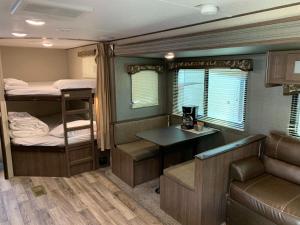 a room with two bunk beds and a desk and a couch at Golden Riverfront Campground in Golden