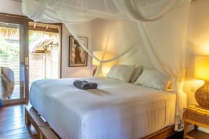 a bedroom with a large white bed with a camera on it at Flow Gili Air in Gili Air