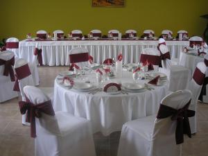 eine Gruppe von Tischen mit weißen Tischdecken und Stühlen in der Unterkunft Hotel Thelena in Tolna