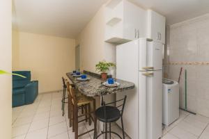 パリョサにあるRental Palhoça- Acomodações Residenciais IIIの冷蔵庫と椅子付きのテーブルがあるキッチン