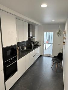 uma cozinha com armários brancos e electrodomésticos pretos em Moodhu Villa - Cozy Apart w/ Amazing Terrace em Leiria