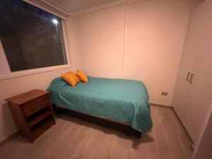 um quarto com uma cama com duas almofadas e uma janela em Cómodo depto cerca de balneareo em Llanquihue