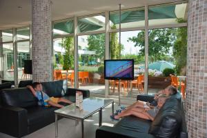 three people sitting on couches in a living room watching tv at Jeravi Club Hotel - All Inclusive in Primorsko