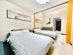 マニラにあるThompson Suites - 2-beds, One Uptown Residences, 30F - XBOX & Netflixのベッド2台とソファが備わるホテルルームです。