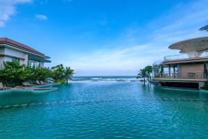 une piscine d'eau à côté d'un bâtiment et de l'océan dans l'établissement KOI Resort & Residence Da Nang, à Đà Nẵng