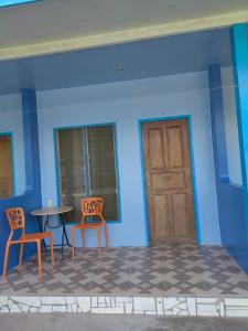 Habitación con 2 sillas, mesa y puerta en Hashtag Tourist Inn, en San Vicente