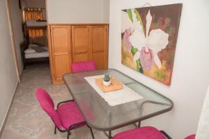 una mesa de comedor con sillas rosas y una pintura en la pared en Marias House - Magnifique Apartments, en Santa Marta
