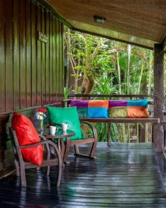 a porch with two chairs and a table and a bed at Little Village Chiang Mai in Chiang Mai