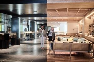 Dos mujeres de pie en una habitación con sofá en The Royal Park Canvas - Kyoto Nijo, en Kioto