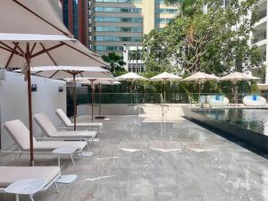 une terrasse avec des chaises et des parasols ainsi qu'une piscine dans l'établissement Floral Court Hotel & Residence Sukhumvit 13, à Bangkok