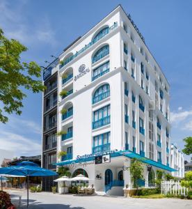 Santori Hotel And Spa في دا نانغ: مبنى ابيض كبير بالبلكونات الزرقاء