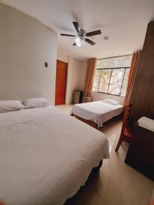 a bedroom with two beds and a ceiling fan at Hospedaje bolognesi in Piura