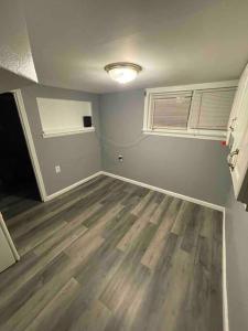 een lege kamer met een hardhouten vloer en een raam bij Cozy and affordable suite (near Rutgers, smartTV) in New Brunswick