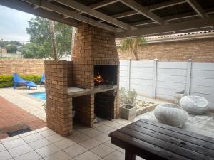 a brick fireplace in a patio with a wooden table at Jbay Tides in Jeffreys Bay