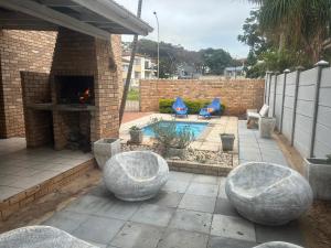 a patio with a fireplace and chairs and a pool at Jbay Tides in Jeffreys Bay