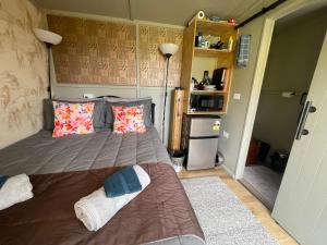a small bedroom with a bed and a refrigerator at Bush Cabin Stunning views in Taumarunui