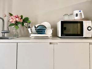 a kitchen counter with a microwave and a vase of flowers at 东京上野秋叶原超豪华双卧套房Ydob 最大8人上野公园3分钟 地铁1分钟位置绝佳超级繁华免费wifi Dyson吹风机 in Tokyo