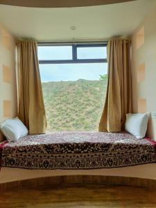 a bed in a room with a large window at The HighGarden Resort in Udaipur