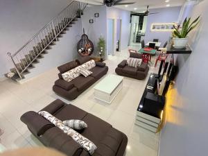 ein Wohnzimmer mit braunen Sofas und einer Treppe in der Unterkunft JJ&KK Homestay in Simpang