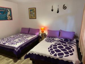 two beds sitting next to each other in a room at La maison près du Phare in Mahina