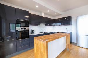 a kitchen with black cabinets and a wooden counter top at Airport Luxury Apartment Prague in Prague