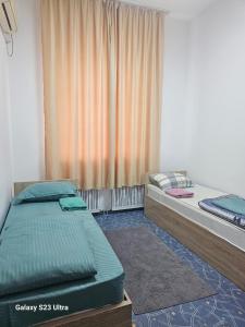 two twin beds in a room with a window at Kamkor in Atyrau