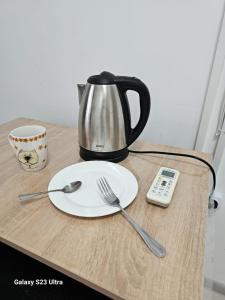 a table with a plate and a coffee pot and a remote control at Kamkor in Atyrau