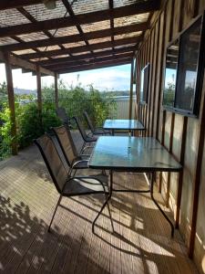 un patio con una mesa de cristal y sillas en una terraza en Pinelodge en Opua