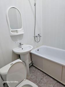 a bathroom with a toilet and a sink and a bath tub at Kamkor in Atyrau