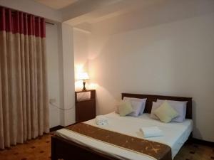 una camera da letto con un letto con una lampada e una finestra di Tenshin Residance. a Kandy