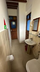 een badkamer met een wastafel, een toilet en een deur bij Light of Zanzibar Hotel in Nungwi