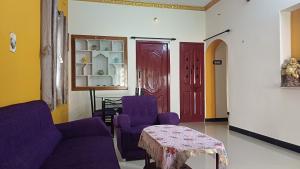 a living room with purple chairs and a table at SHI's Malli 1BHK Home in Coimbatore City 