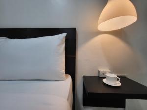 Una cama con una taza sobre una mesa con una lámpara en Rooms R Us - Evangelista en Manila