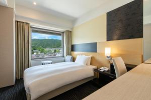 a hotel room with a large bed and a window at Kyoto Yamashina Hotel Sanraku in Kyoto