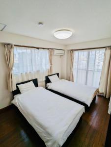 2 camas en una habitación con ventanas en Fieldnever Apartment STAY - Maisonette Family room en Fukuoka