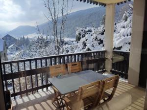 una mesa y sillas en un balcón con montañas cubiertas de nieve en L'Appart de Villard en Villard-de-Lans