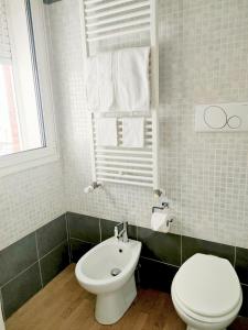 La salle de bains blanche est pourvue de toilettes et d'un lavabo. dans l'établissement Appartamento con terrazzo privato Milano San Raffaele Linea verde, à Vimodrone