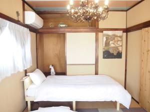 1 dormitorio con cama y lámpara de araña en Classy仏生山, en Takamatsu