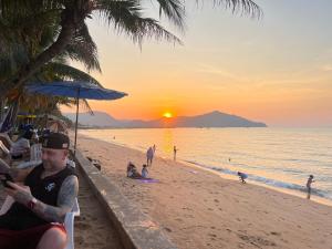 een man die op een strand zit te kijken naar de zonsondergang bij Bangsaray Beach Resort in Bang Sare