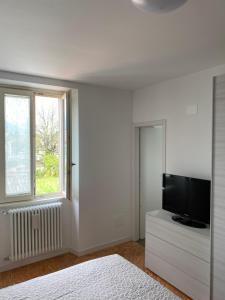 ein weißes Schlafzimmer mit einem Flachbild-TV auf einer Kommode in der Unterkunft Cozy Escape in Bellagio in Bellagio